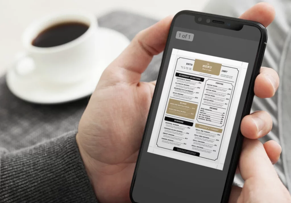 A diner holding their mobile phone in hand trying to read a tiny PDF menu