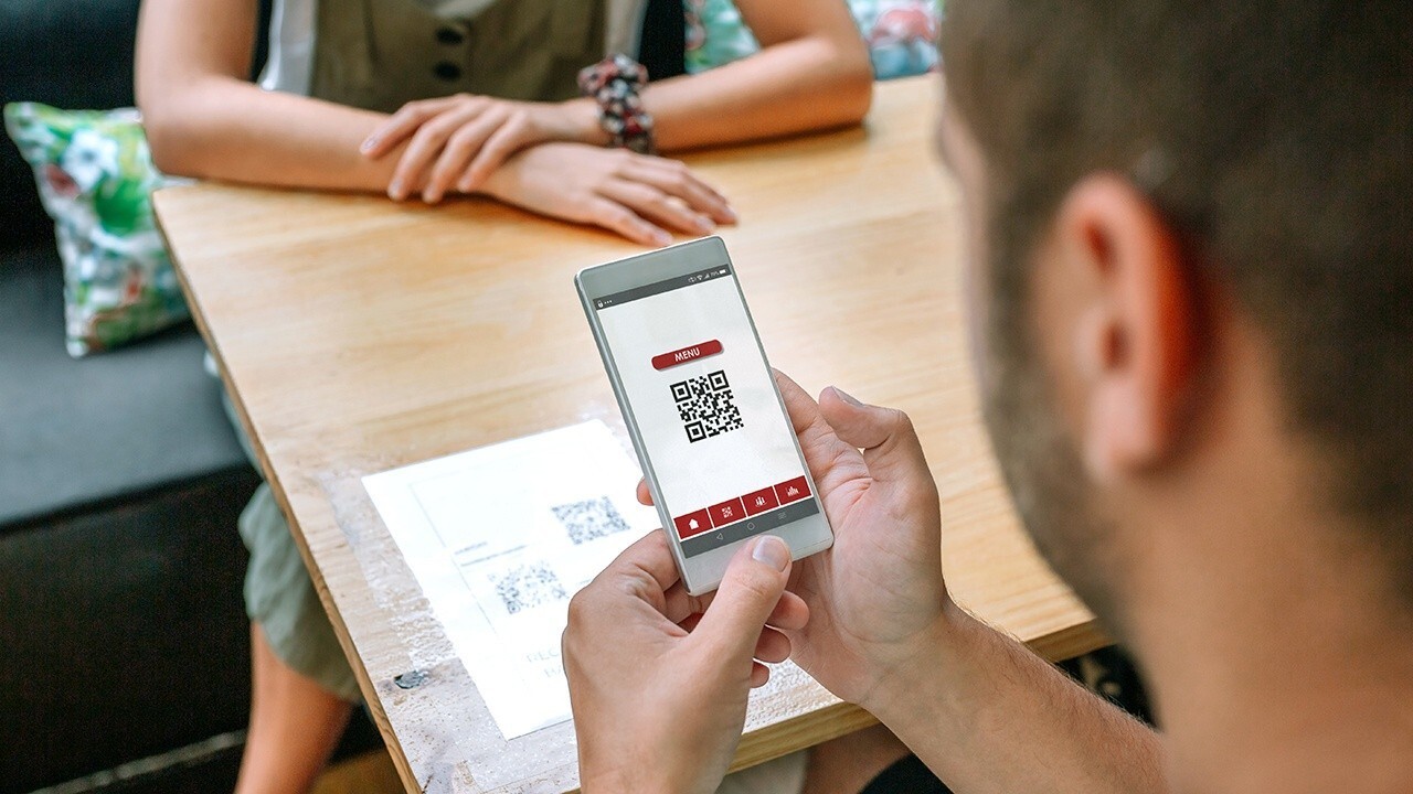 A restaurant diner views a QR code on their phone just before clicking to bring up the restaurant’s QR code menu