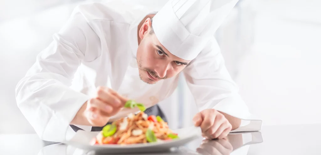 A chef, aware of sensory marketing techniques, carefully attends to the visual elements of plating