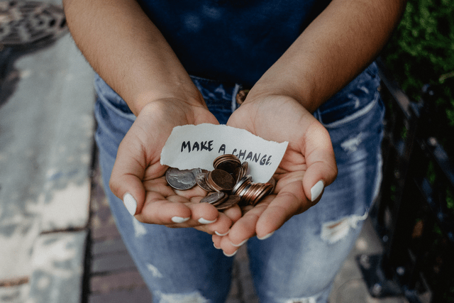 Image of hands holding coins and a piece of paper with the words 