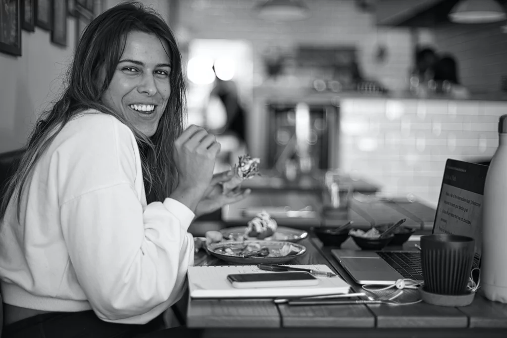 A woman smiles happily at a restaurant table, representing the benefits of emotional marketing in restaurants