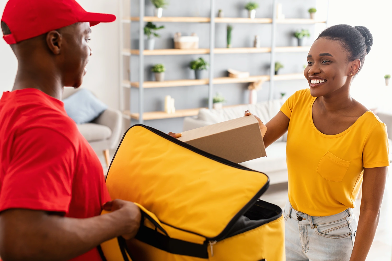 Giving guests the ability to order online and have food delivered opens restaurants to significantly more revenue. In this image, a smiling delivery driver hands a delivery to a consumer.