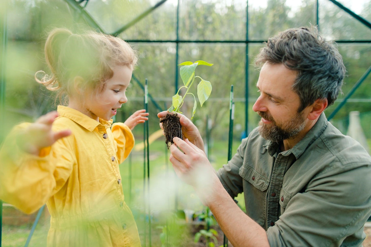 A man showing a plant to a girl in a greenhouse, perhaps he's thinking about culinary creativity.