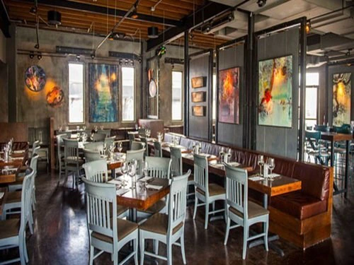 Inside the restaurant R House, Miami - showcasing tables, chairs, and paintings on the walls