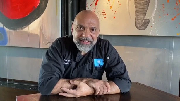 Chef Rocco Carulli sitting at a table inside his Miami restaurant, R House, contemplating the challenges of restaurant ownership with resilience.