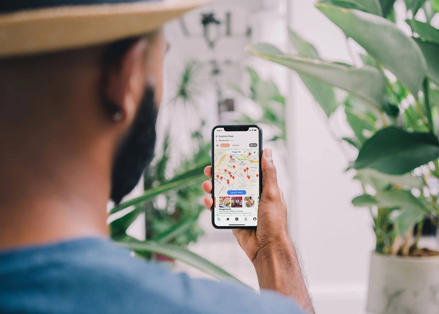 A man with a hat is looking at a map on his phone to find restaurant loyalty rewards.