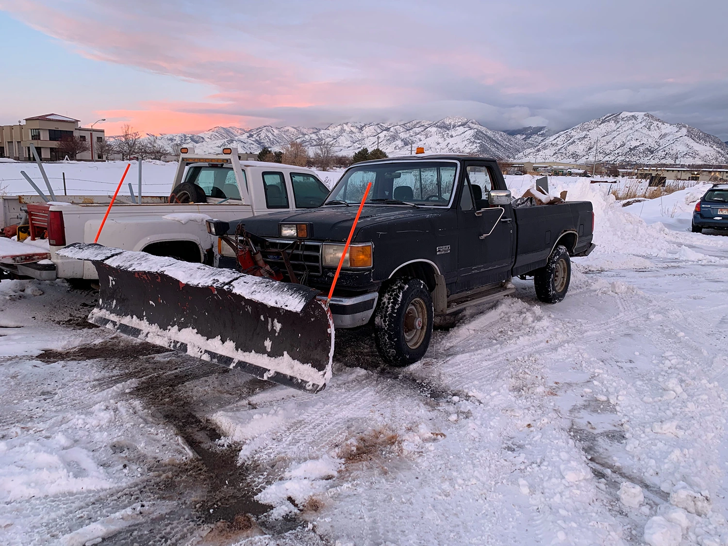 A truck with a plow parked in the snow.