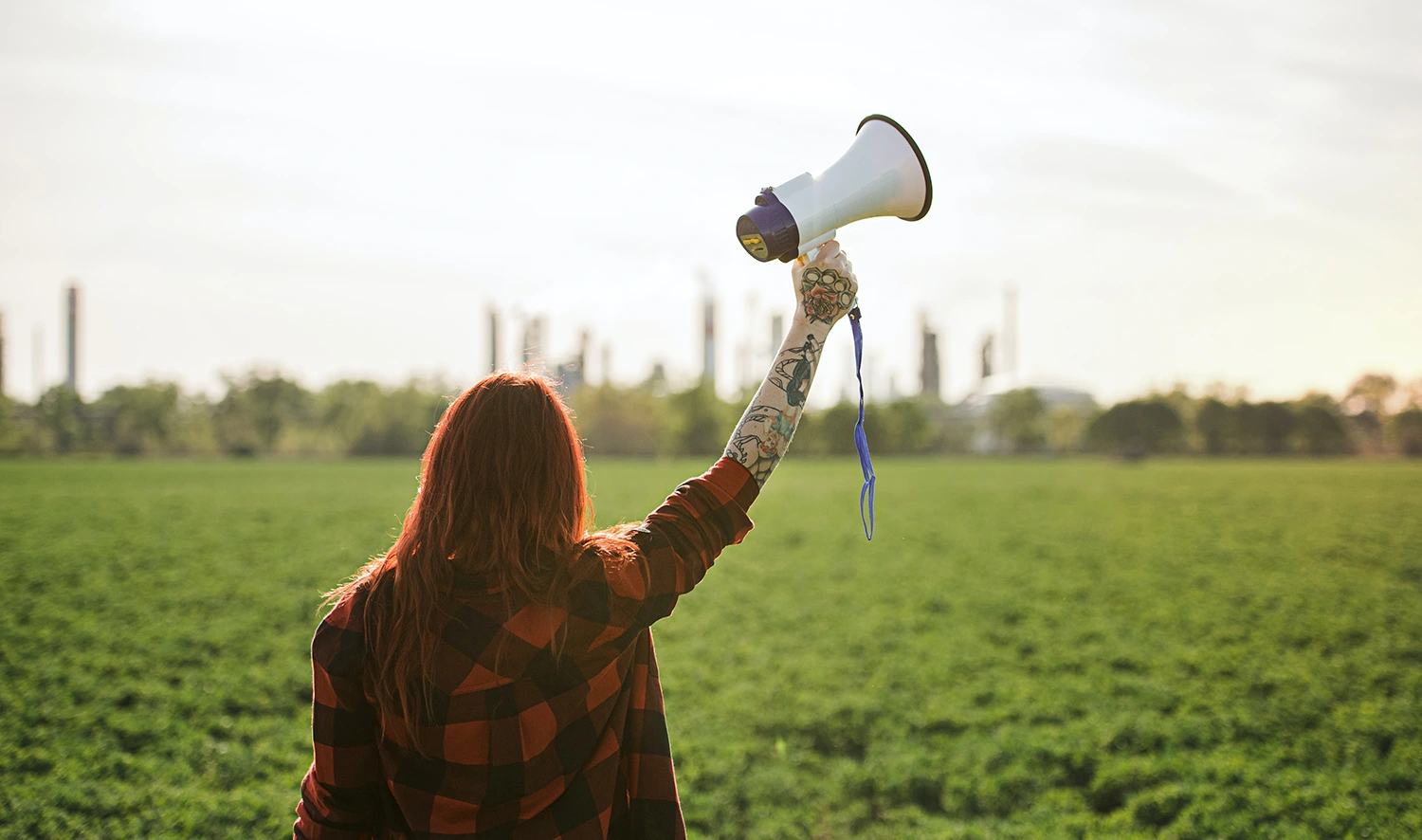 A woman holding a megaphone in a field representing the promotion of a restaurant loyalty program.