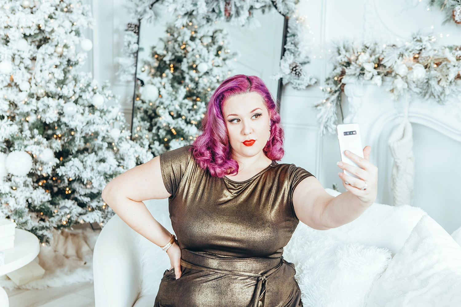 A woman taking a selfie in front of a Christmas tree during the holiday season.