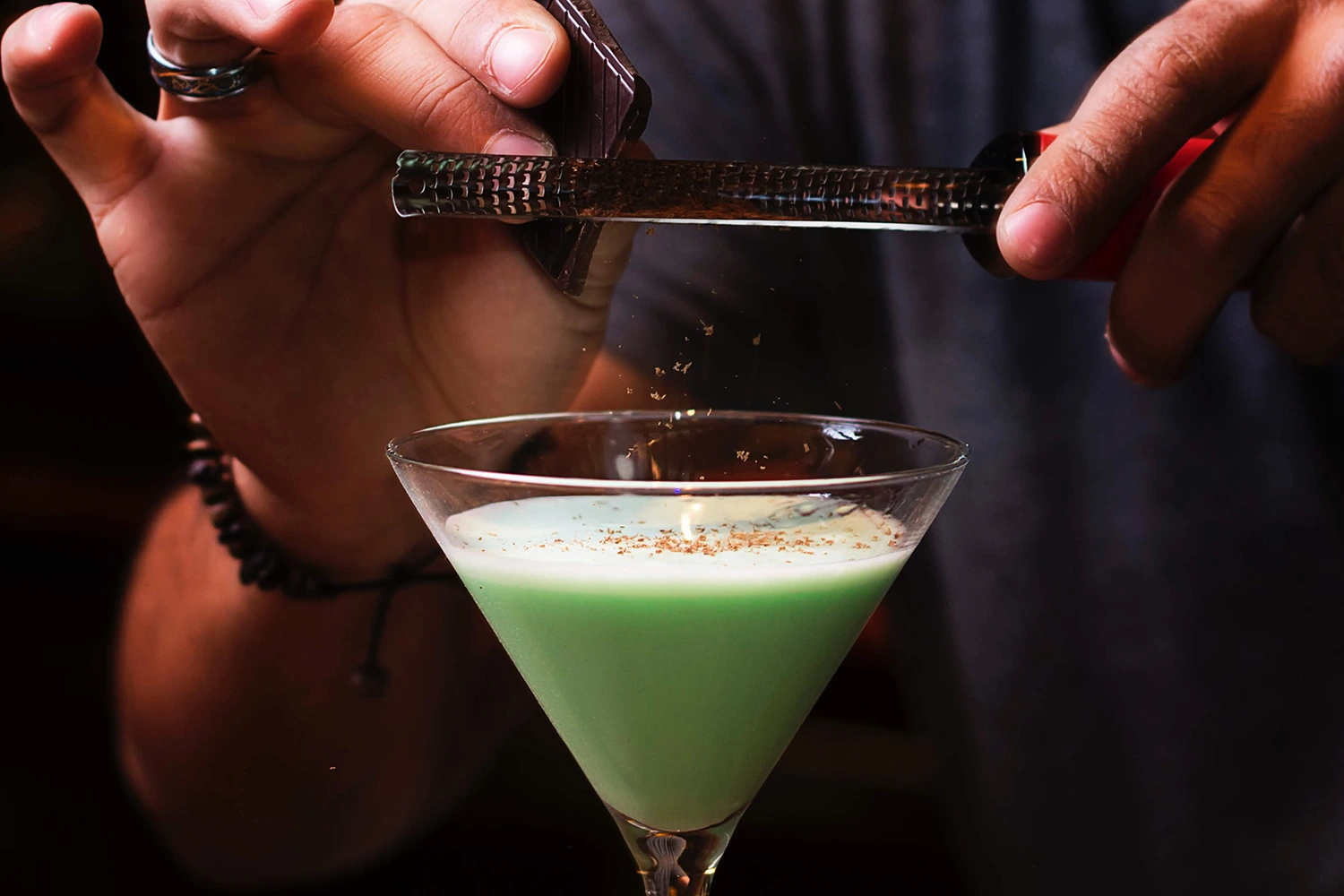A person is making a green drink in a glass to increase restaurant loyalty.