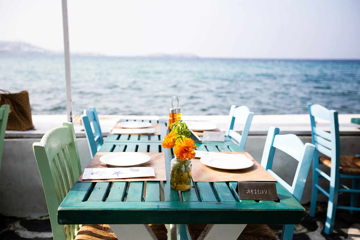 A blue table and chairs on a deck overlooking the ocean at an outdoor eatery.