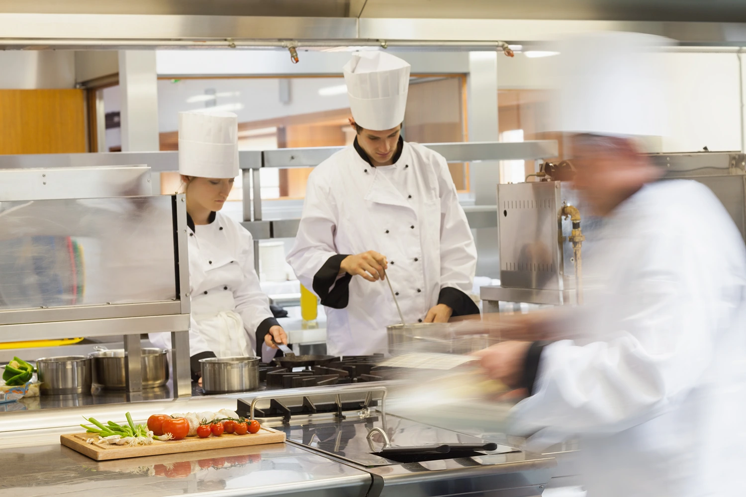 A group of chefs preparing food in a commercial kitchen while considering menu pricing and restaurant profit margins.