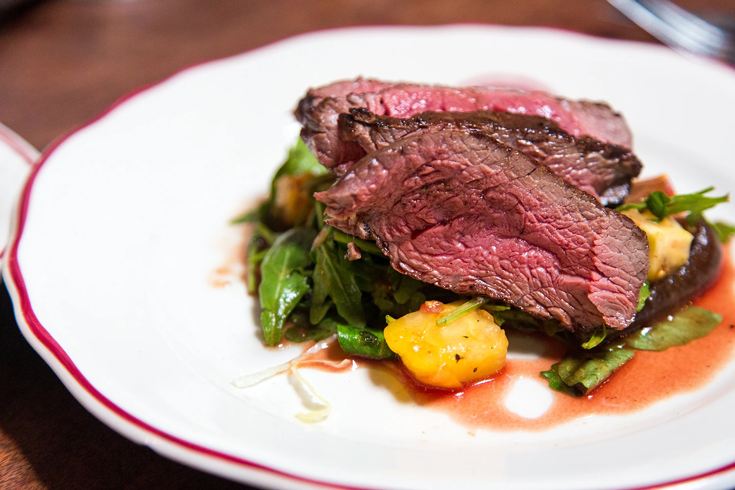 A plate with steak and vegetables on it. As the cost of beef rises, consider what to do to manage your restaurant's fluctuating ingredient costs.